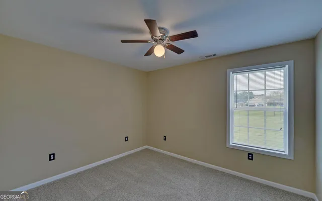 an empty room with ceiling fan and window