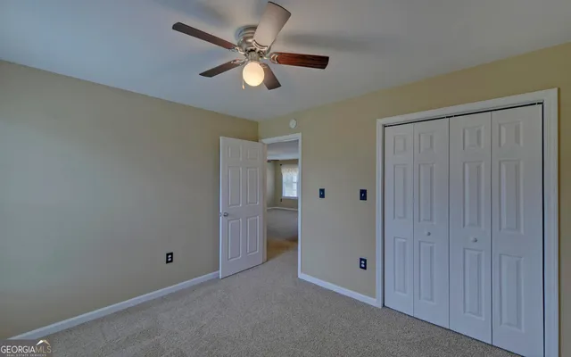 an empty room with closet and a chandelier fan