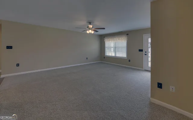 an empty room with a window and a ceiling fan