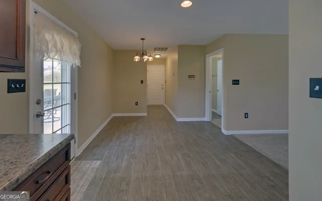 a view of a hallway with wooden floor and chandelier