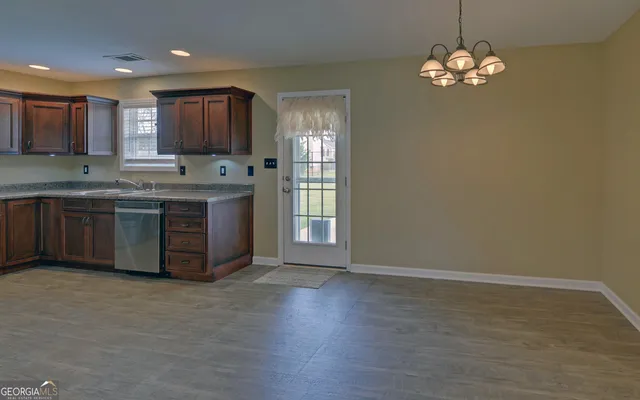 a large kitchen with stainless steel appliances granite countertop a sink dishwasher a stove and a dining table with wooden floor