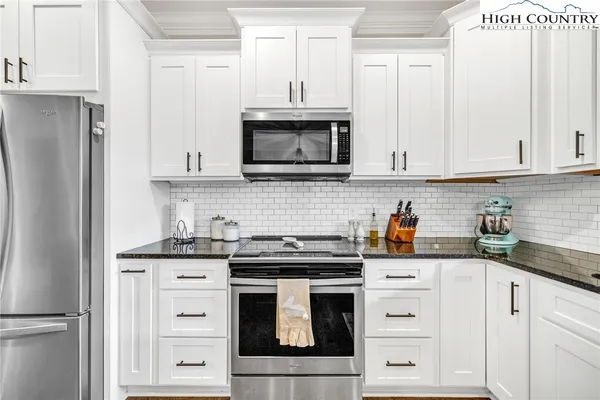 a kitchen with granite countertop white cabinets and stainless steel appliances