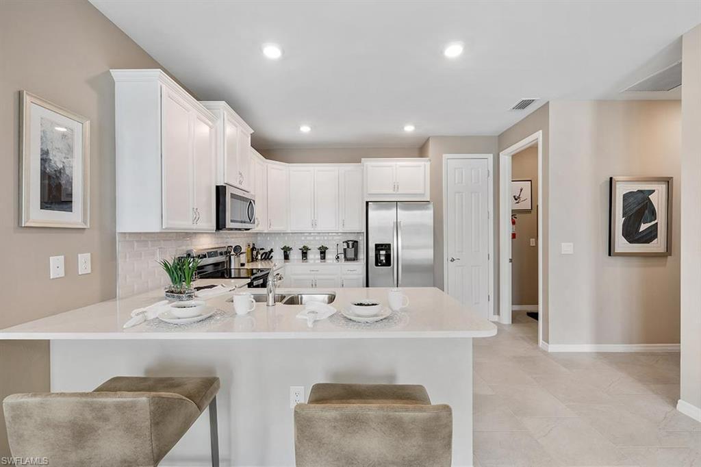 922 Enbrook Loop, Unit 46 Naples, FL 34114 - Photo 4 of 31 a kitchen with kitchen island stainless steel appliances a sink and cabinets