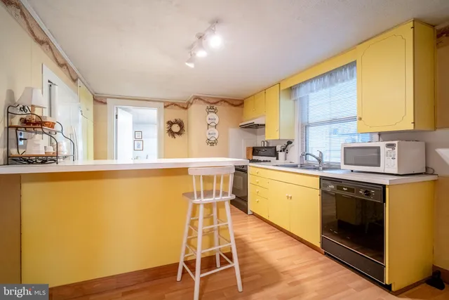 a kitchen with wooden floors and white stainless steel appliances