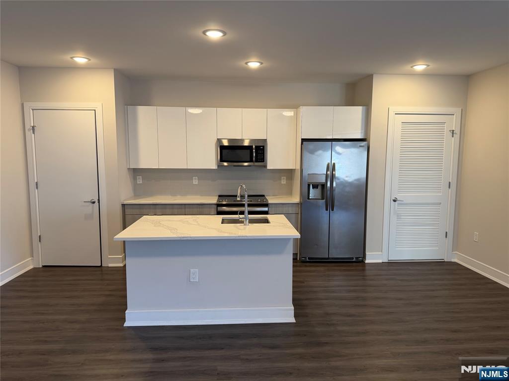 a view of kitchen with stainless steel appliances wooden floor and living room view