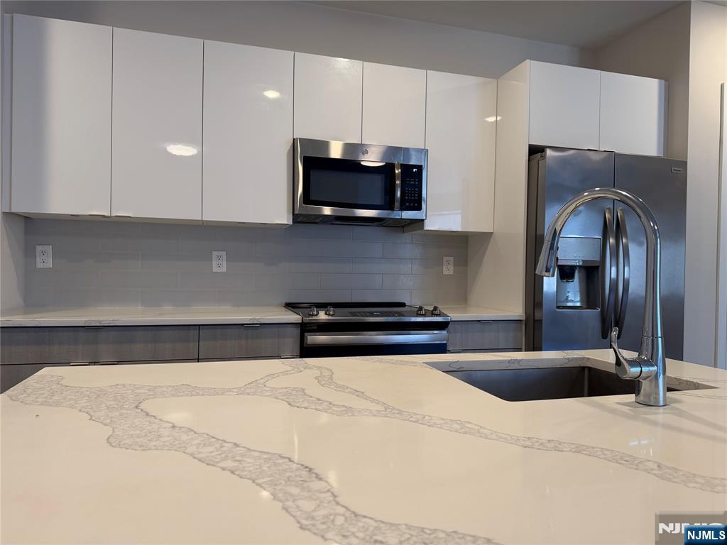 470 Main Street, Unit 703 Fort Lee, NJ 07024 - Photo 3 of 19 a kitchen with stainless steel appliances kitchen island granite countertop a stove a sink and a microwave