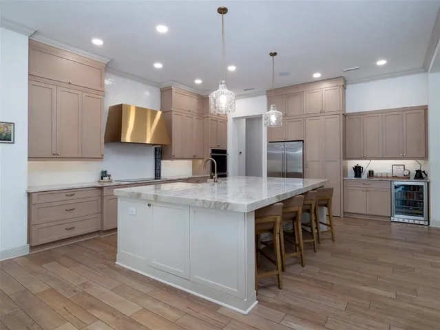 a large kitchen with cabinets chairs and wooden floor