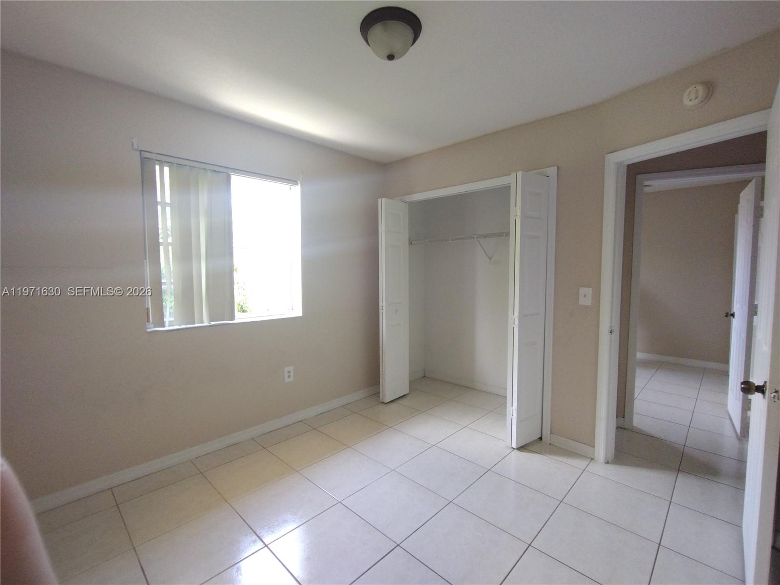 6756 Northwest 182nd Street, Unit 101 Hialeah, FL 33015 - Photo 17 of 29 a view of an empty room with window and a chandelier fan