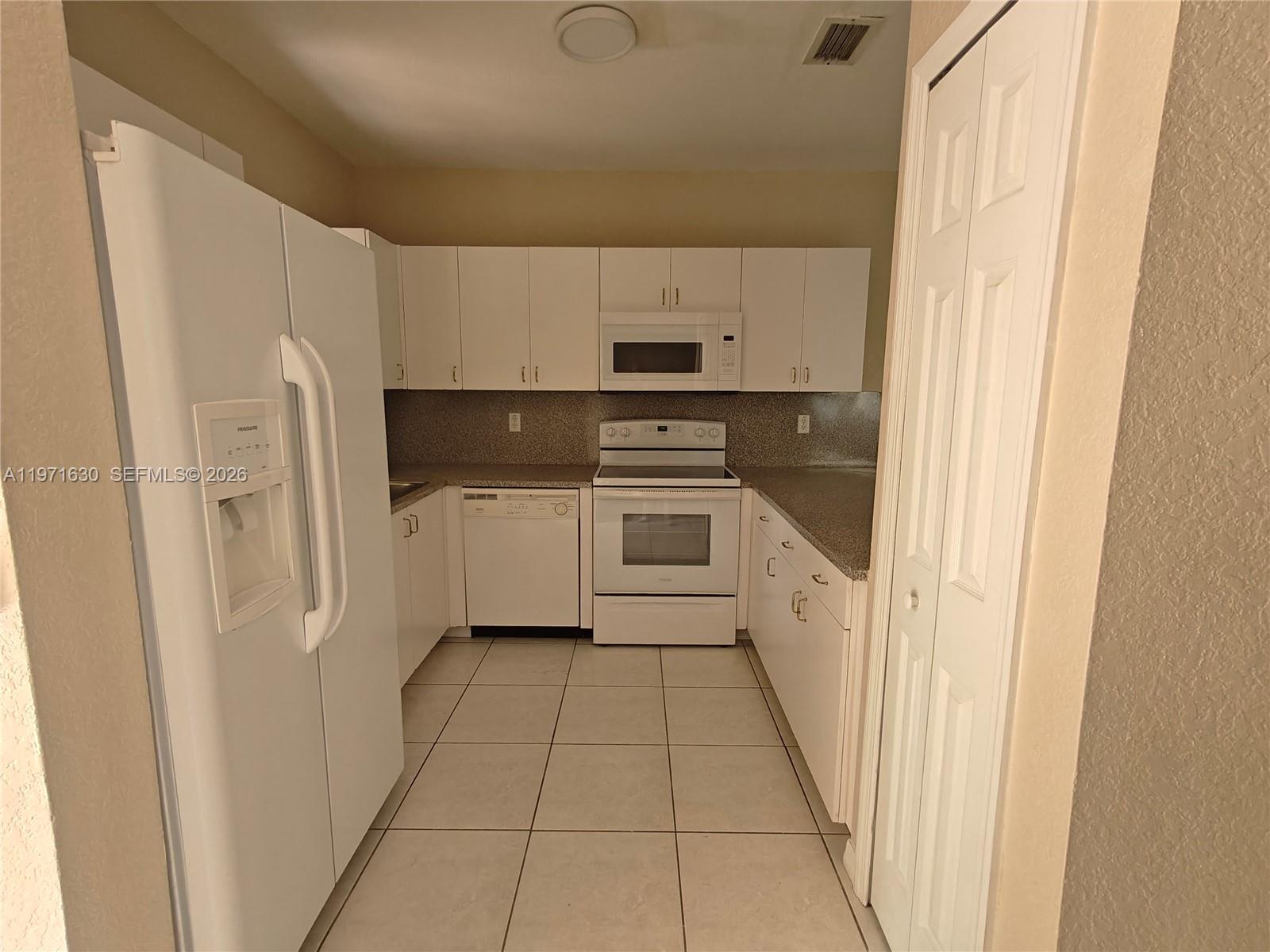 6756 Northwest 182nd Street, Unit 101 Hialeah, FL 33015 - Photo 5 of 29 a kitchen with a refrigerator a stove top oven