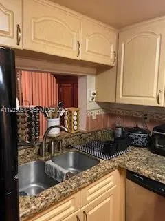 a kitchen with granite countertop a sink a stove and cabinets