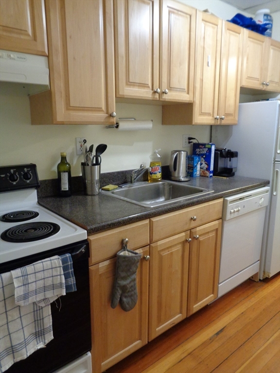 40 Carlton Street, Unit 10 Brookline, MA 02446 - Photo 2 of 11 a kitchen with granite countertop white cabinets and white appliances