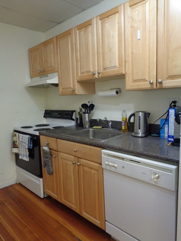 40 Carlton Street, Unit 10 Brookline, MA 02446 - Photo 6 of 11 a kitchen with stainless steel appliances granite countertop a sink and cabinets with wooden floor