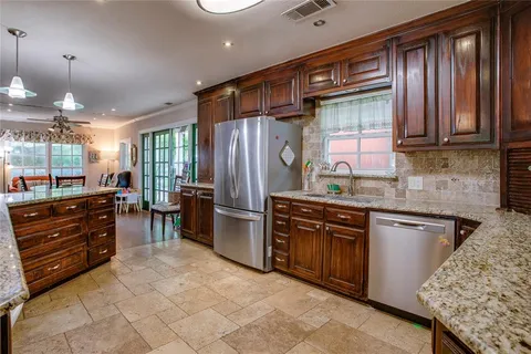 a kitchen with granite countertop cabinets a sink stainless steel appliances and windows