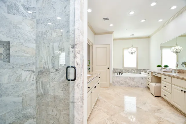 a bathroom with a granite countertop tub shower and mirror