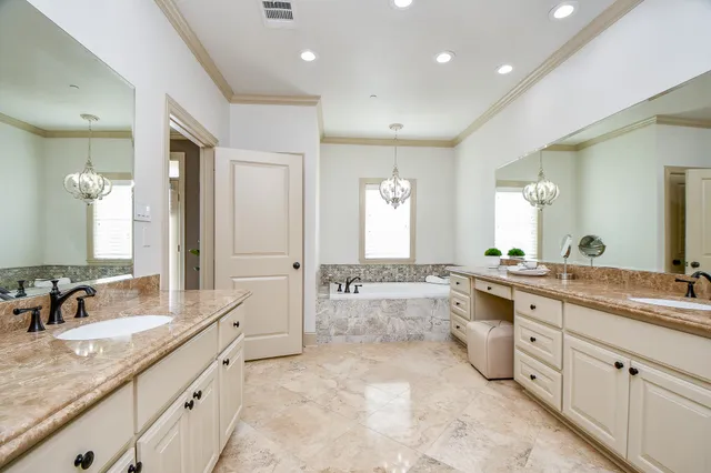 a large bathroom with a granite countertop double vanity sink a large mirror and a bathtub
