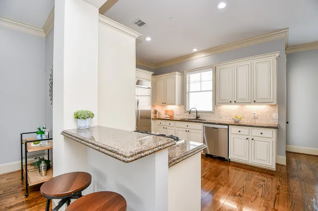 a kitchen with granite countertop a sink white cabinets a stove a dining table and chairs