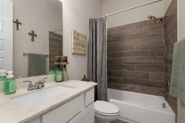 a bathroom with a granite countertop bathtub shower sink vanity and toilet