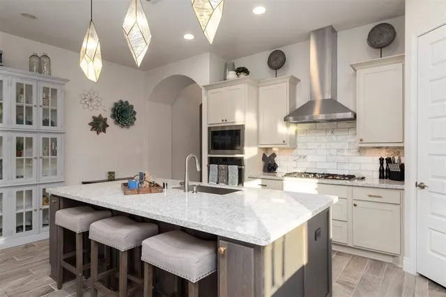 a kitchen with stainless steel appliances kitchen island granite countertop a table chairs in it and wooden floors