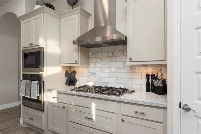 a kitchen with granite countertop a stove and white cabinets