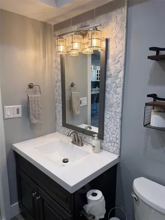 a bathroom with a sink a toilet a mirror and shower