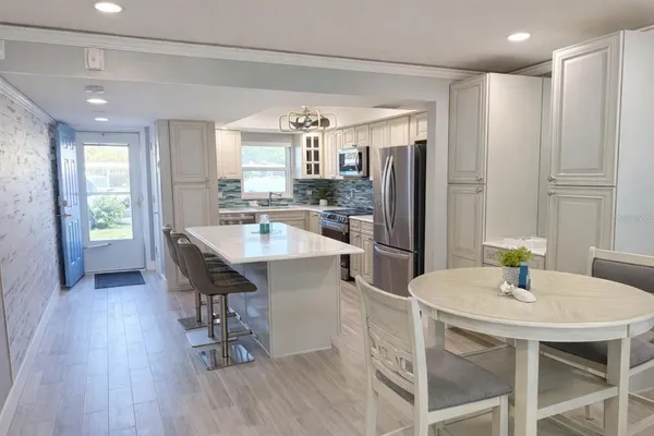 a kitchen with stainless steel appliances a dining table chairs and wooden floor