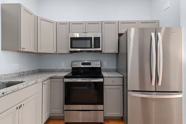a kitchen with stainless steel appliances granite countertop a refrigerator stove and white cabinets