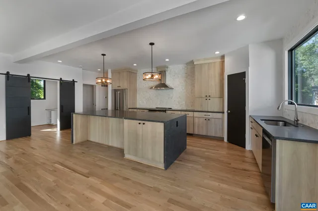 a large kitchen with granite countertop a large counter top stainless steel appliances and cabinets