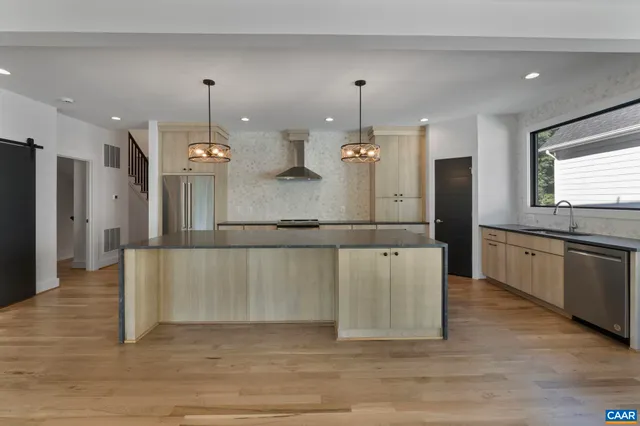 a view of a kitchen center island wooden floor and stainless steel appliances