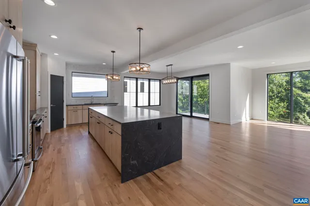 a large kitchen with stainless steel appliances a large counter top a sink a refrigerator and a window