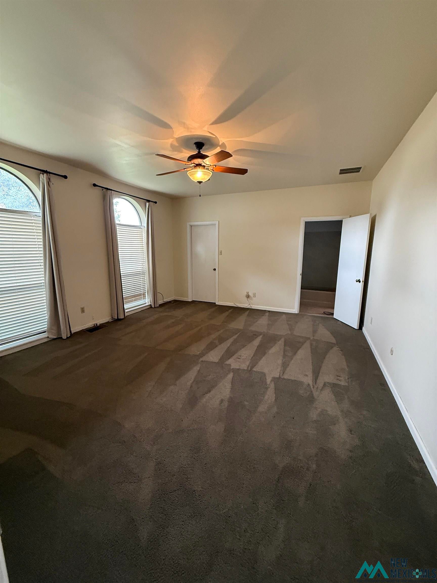 1111 West Country Road Roswell, NM 88201 - Photo 40 of 41 Spacious room featuring dark carpeting, light-toned walls, and a ceiling fan with integrated lighting