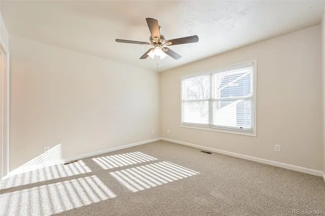 an empty room with windows and fan