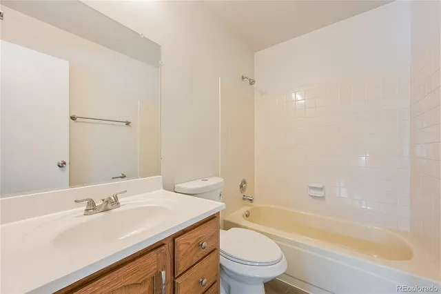 a bathroom with a bathtub shower sink vanity mirror and toilet