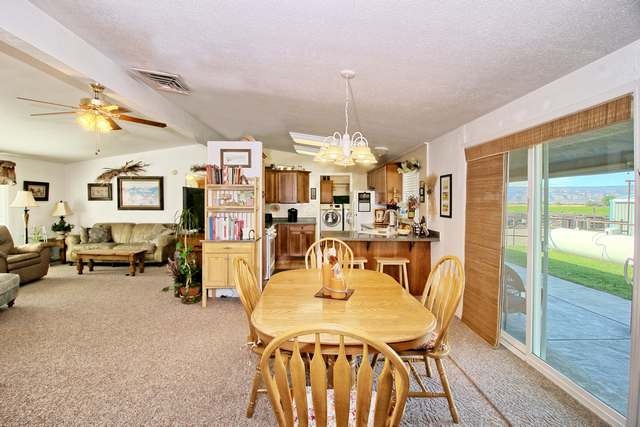 2135 M Road Grand Junction, CO 81505 - Photo 30 of 42 a view of a dining room and livingroom with furniture wooden floor a rug a flat screen tv a painting and a chandelier