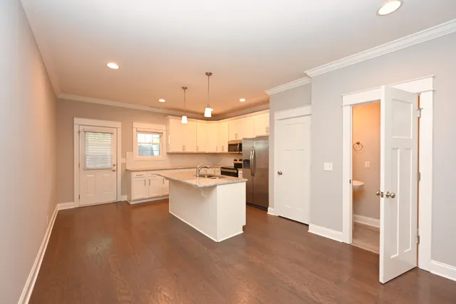 a view of an empty room with wooden floor and a ceiling fan