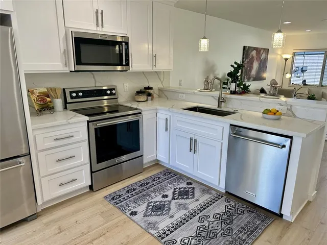 a kitchen with stainless steel appliances white cabinets and a stove a oven with wooden floor