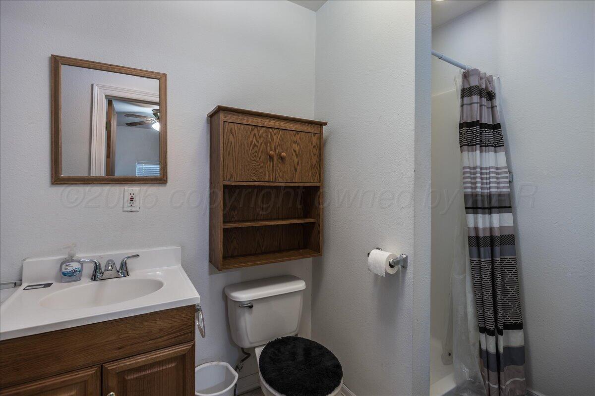 4011 Parker Street Amarillo, TX 79110 - Photo 14 of 17 a bathroom with a toilet a sink and mirror