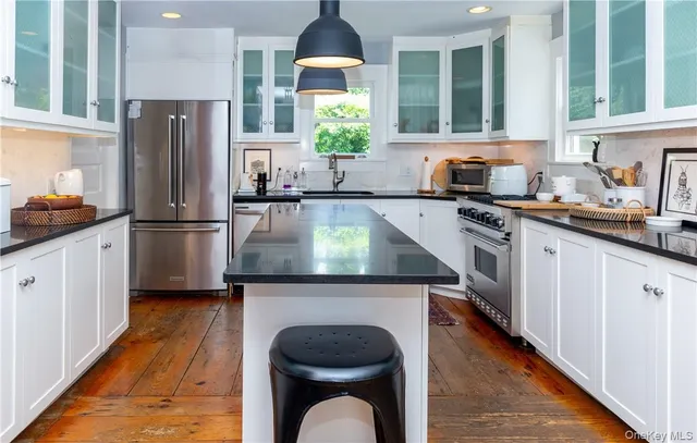 a kitchen with kitchen island granite countertop a stove refrigerator and sink