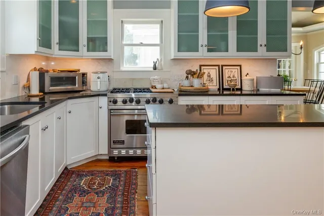 a kitchen with stainless steel appliances granite countertop a sink and a stove next to a window