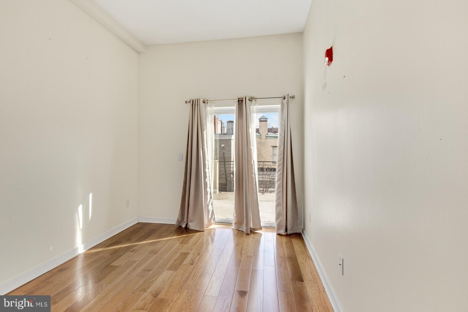 2031 South Juniper Street, Unit 204 Philadelphia, PA 19148 - Photo 18 of 31 an empty room with wooden floor and windows