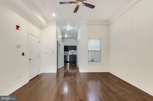 a view of empty room with wooden floor and fan