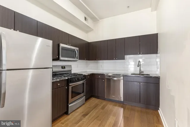 a kitchen with granite countertop a refrigerator stove top oven and sink