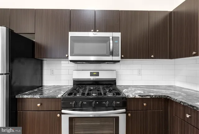 a kitchen with granite countertop a stove and a microwave