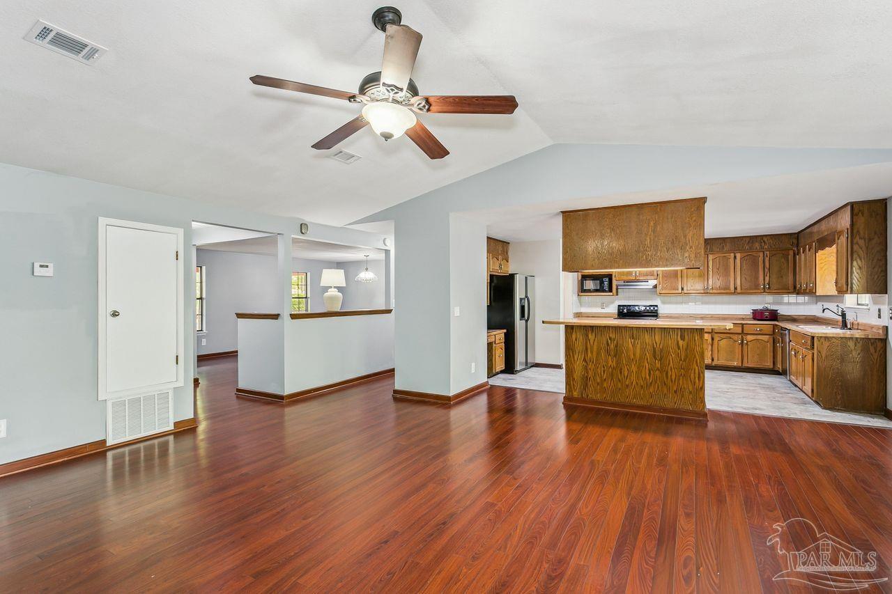 111 Cotton Creek Road McDavid, FL 32568 - Photo 12 of 37 a living room with stainless steel appliances kitchen island granite countertop wooden floors and a fireplace
