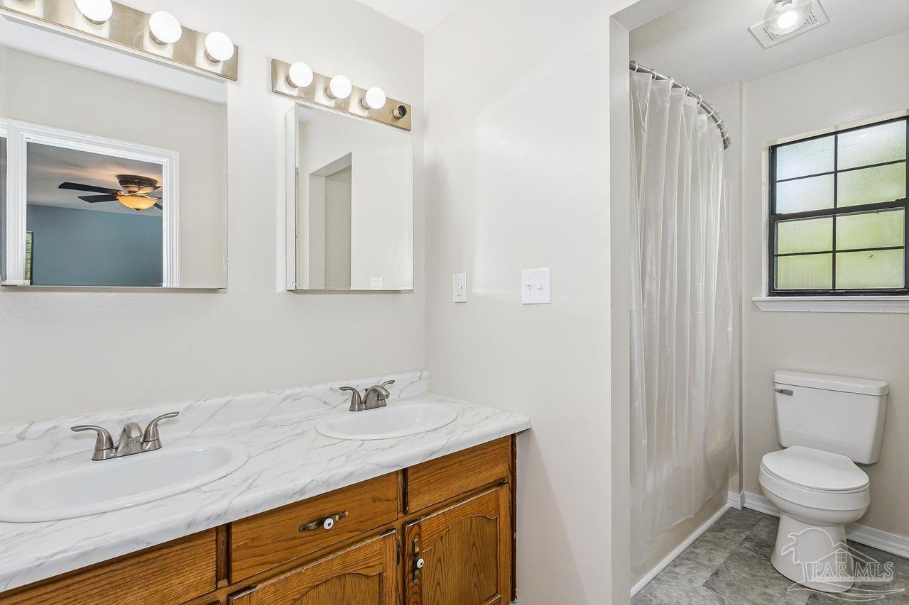 111 Cotton Creek Road McDavid, FL 32568 - Photo 24 of 37 a bathroom with a granite countertop sink a toilet and a mirror