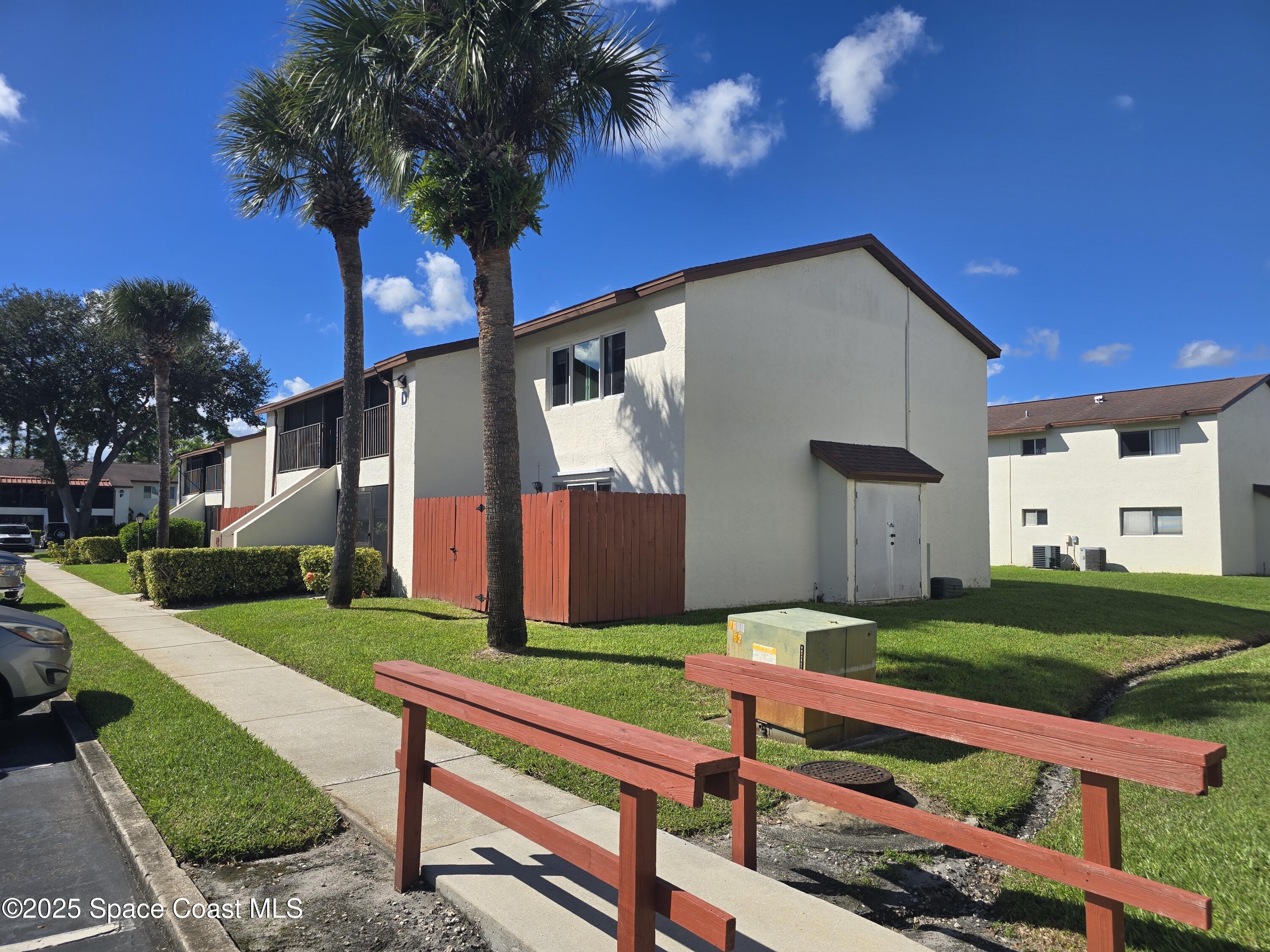 620 Ridge Club Drive, Unit 88 Melbourne, FL 32934 - Photo 2 of 18 a wooden bench sitting in front of a house with a yard