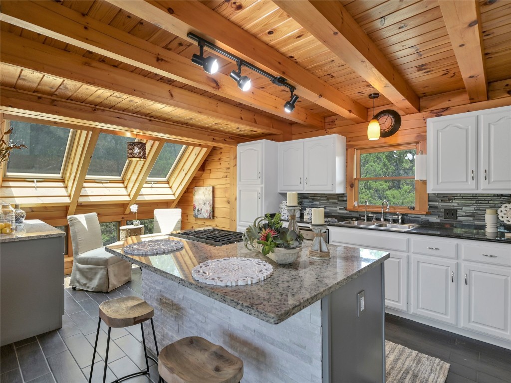 18304 West Reed Park Road Jonestown, TX 78645 - Photo 6 of 24 Rich wood beams span the ceiling above a modern island and stone countertops.