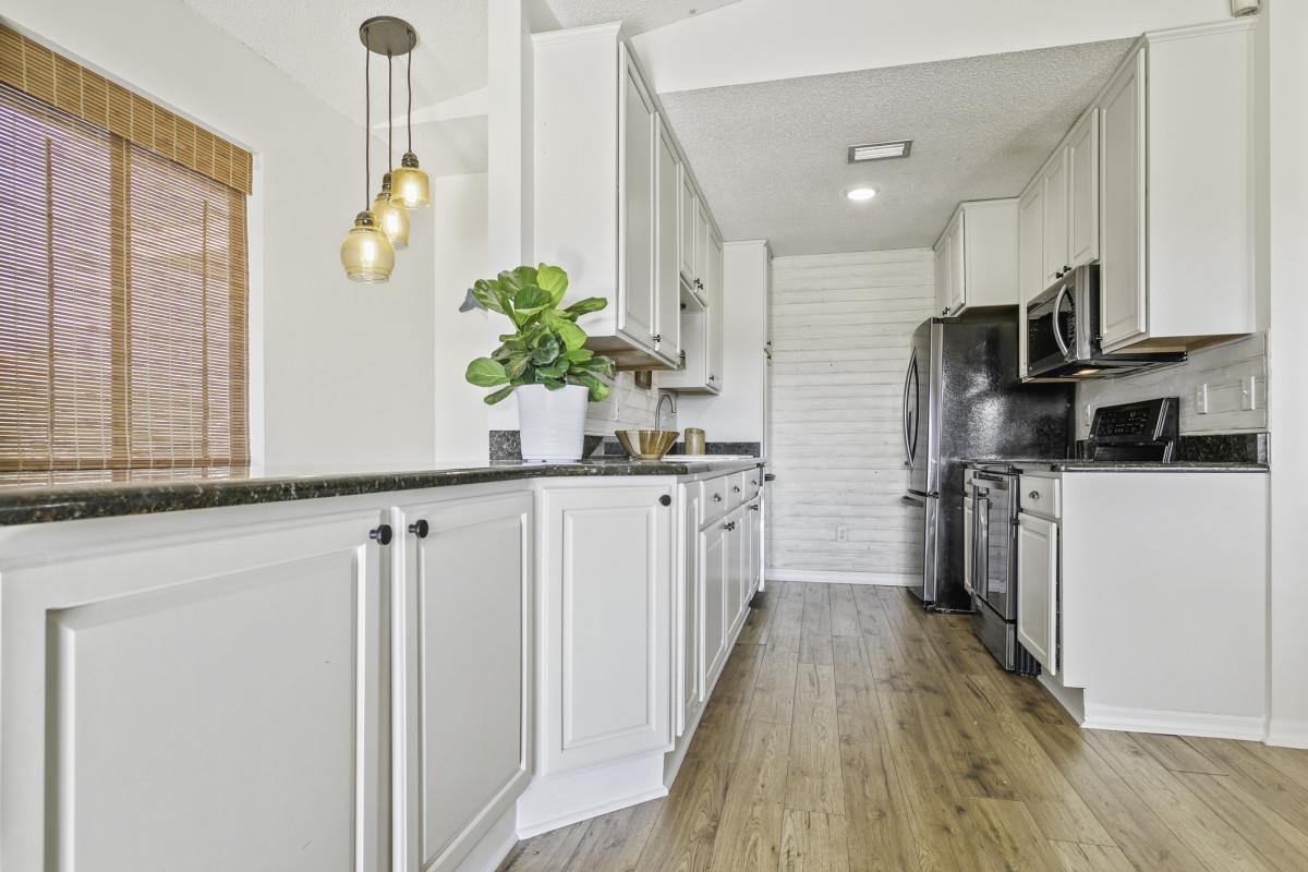 5484 5th Street St. Augustine, FL 32080 - Photo 14 of 37 a kitchen with white cabinets and stainless steel appliances