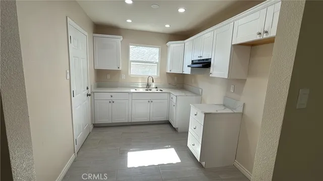 a kitchen with white cabinets sink and refrigerator