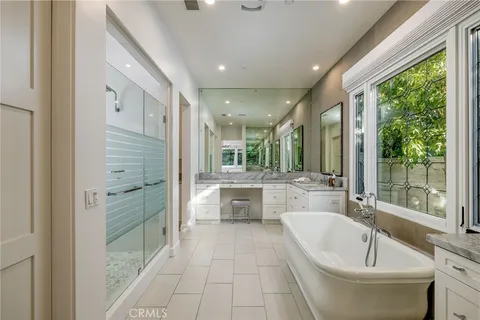 a bathroom with a tub a sink a mirror and a large window