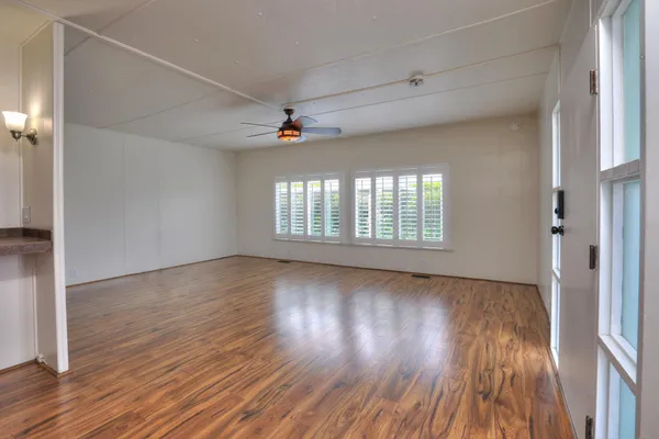 a view of an empty room with window and wooden floor